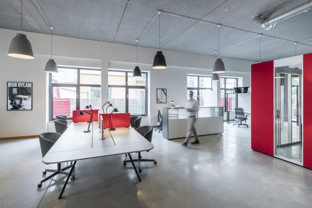 Workstations with red privacy screens, reception desk behind them and a red telephone box