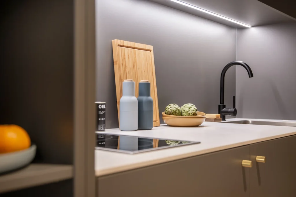 Kitchen detail with stove, cutting board, spice mill and black faucet in Apartment S, ipartment Berlin Airport