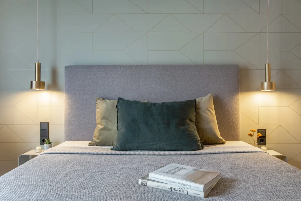 Boxspring bed with pillows and two brass pendant lights above the nightstands in Apartment S, ipartment Berlin Airport