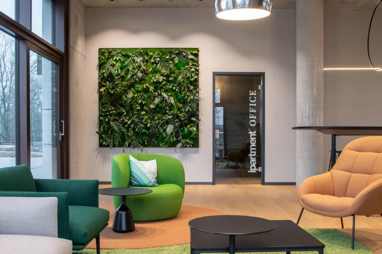Lounge corner with green armchair, plant wall and glass door to the ipartment Office, ipartment Berlin Airport