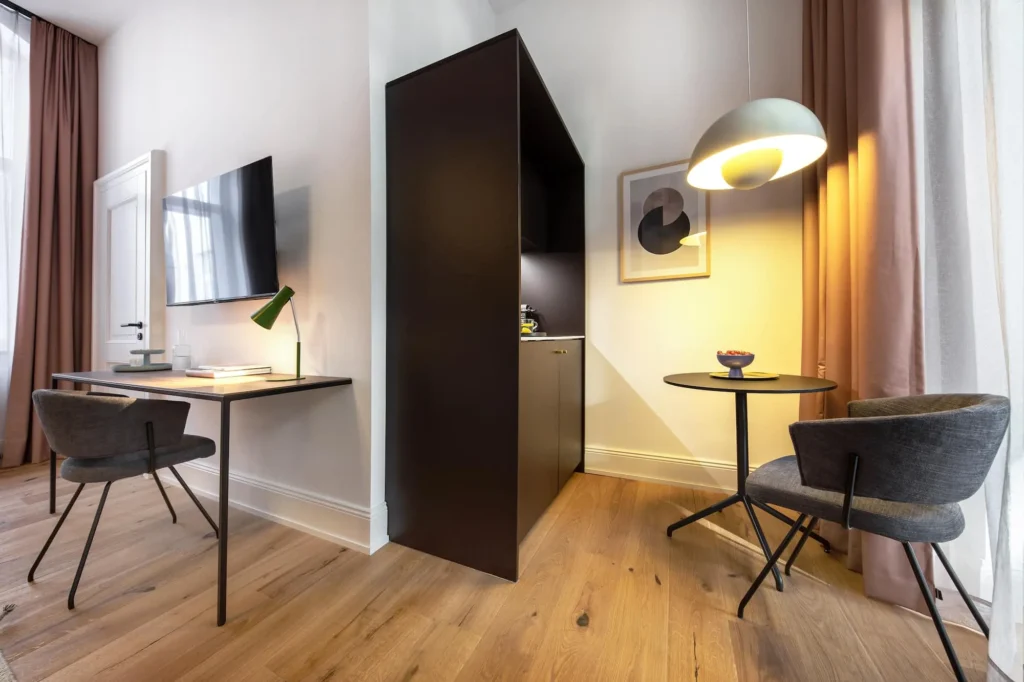 Sitting area with two chairs, work desk, floor lamp and TV in the Medium apartment, ipartment Berlin Kurfürstendamm