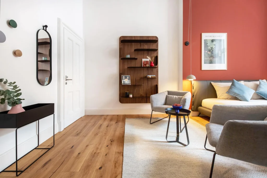 Living area with sofa, armchairs, wooden wall shelf and parquet floor in the Smart apartment, ipartment Berlin Kurfürstendamm