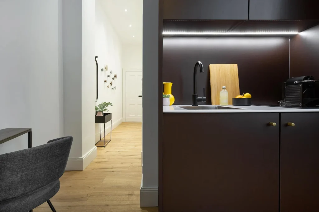 Dark kitchen area with lighting and view into the hallway in the Xtra Smart apartment, ipartment Berlin Kurfürstendamm