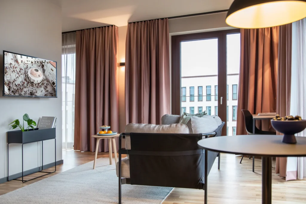 Living area with sofa, dining table and balcony door with curtains in Apartment L, ipartment Berlin Mitte