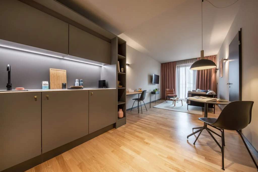Long kitchen area, work area and dining area in the open living space of the L apartment, ipartment Berlin Mitte