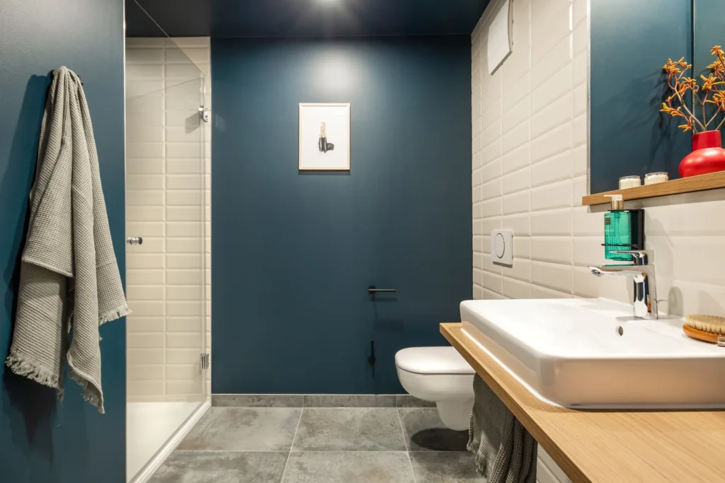 Bathroom with sink, shower and petrol-colored wall in Apartment L, ipartment Berlin Mitte