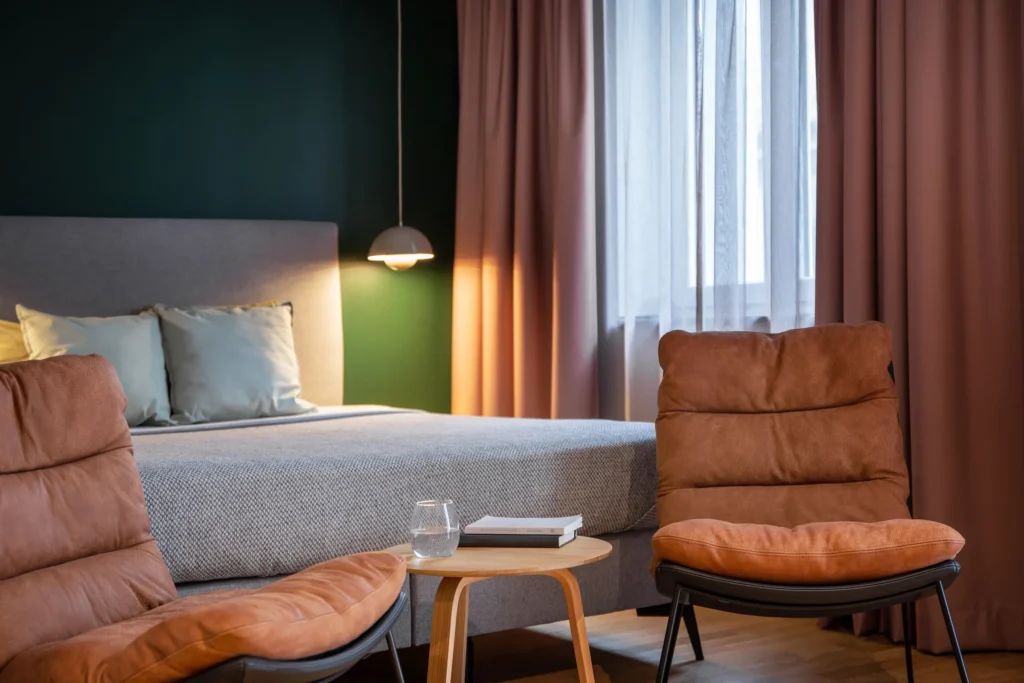 Double bed with two armchairs and a side table in front of the window in Apartment S, ipartment Berlin Mitte