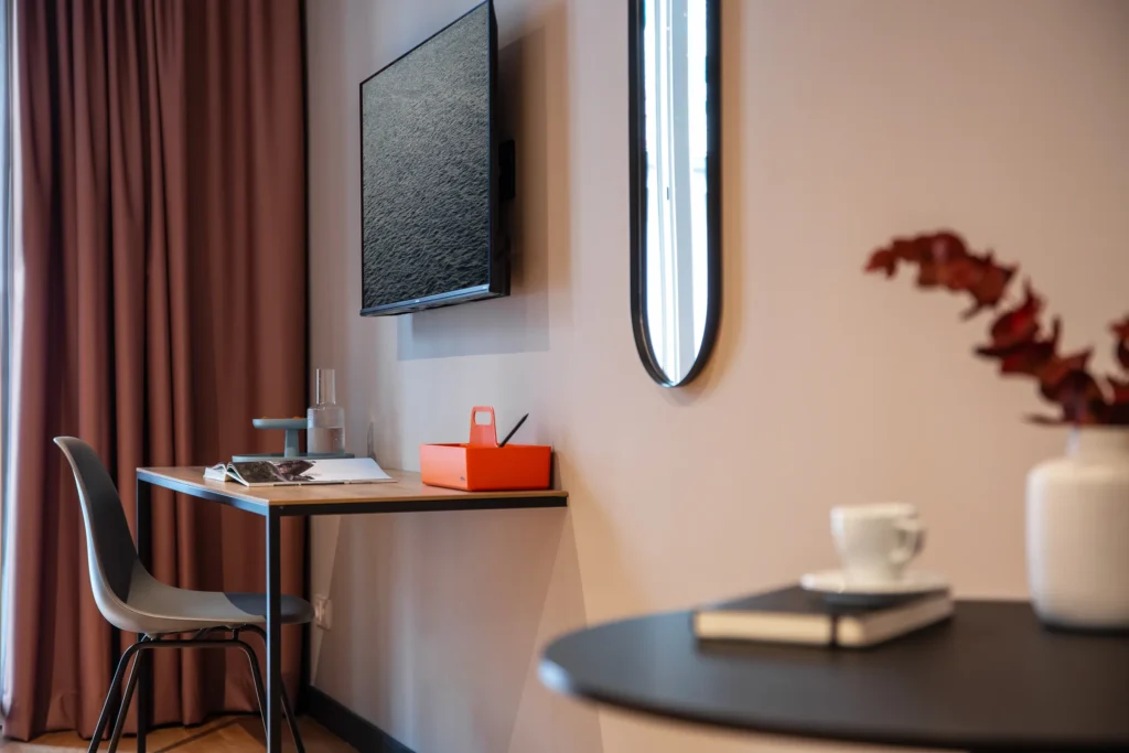 Workplace with desk, chair, TV and oval mirror in apartment S+, ipartment Berlin Mitte