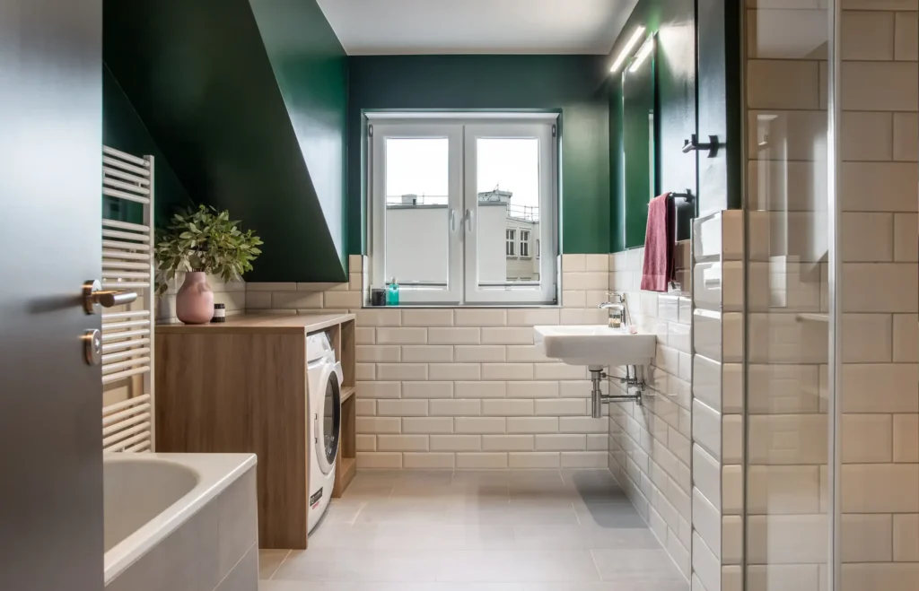 Bathroom with bathtub, washing machine, sink and sloping roof in the XL apartment, ipartment Berlin Mitte