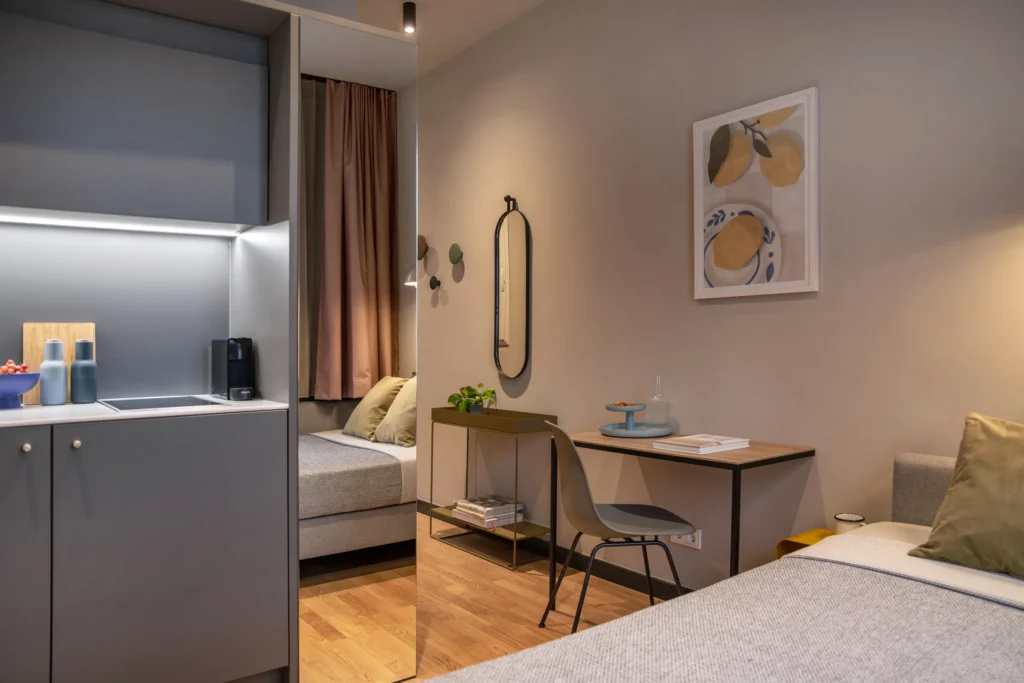 Living and sleeping area with kitchenette, desk and bed in the XS apartment, ipartment Berlin Mitte