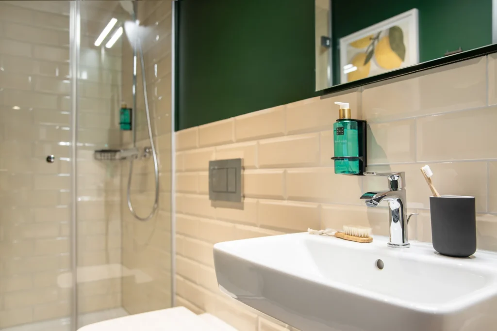 Bathroom with shower, sink and bright Metro tiles in the XS+ apartment, ipartment Berlin Mitte