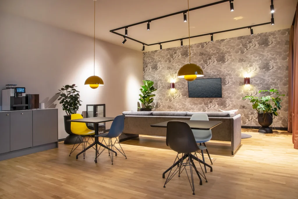 Lounge with sofa, tables, chairs and coffee machine under yellow pendant lights, ipartment Berlin Mitte
