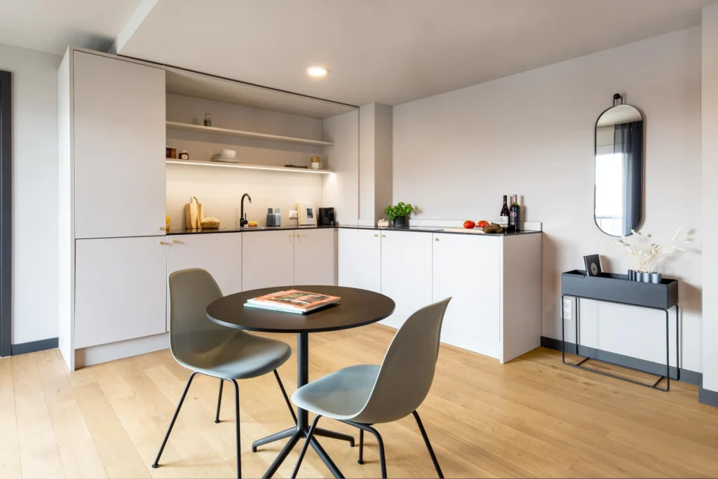 Kitchenette with shelves and round dining table with two chairs in the Luxury apartment, ipartment Böblingen-Sindelfingen
