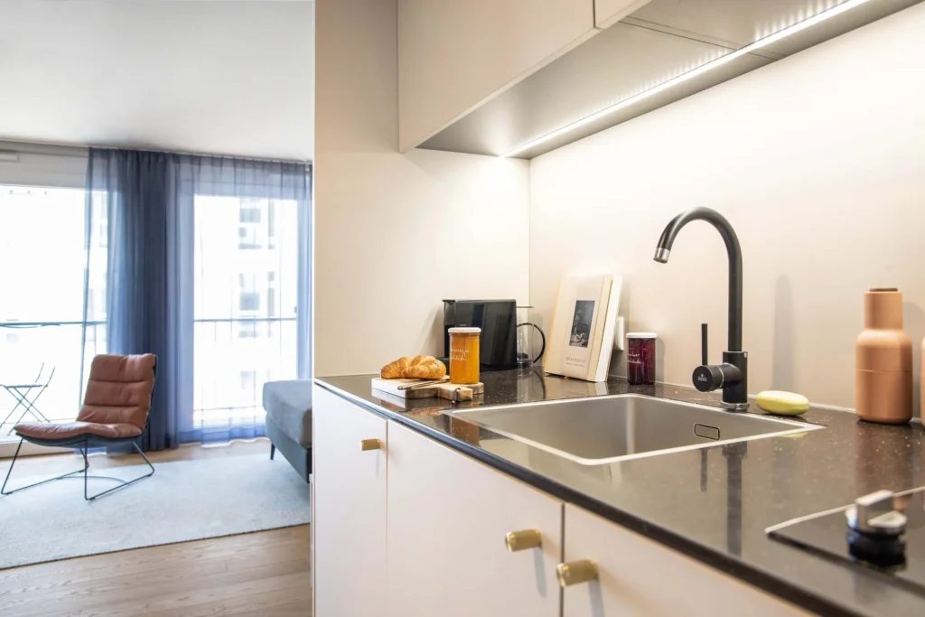 Kitchenette with sink and croissant; in the background, a chair on the balcony window in the Smart apartment, ipartment Böblingen-Sindelfingen