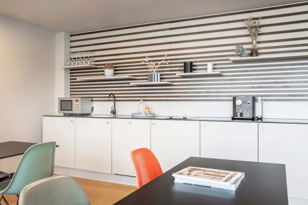 Lounge with kitchenette, striped wall and colorful chairs at the dining table, ipartment Böblingen-Sindelfingen