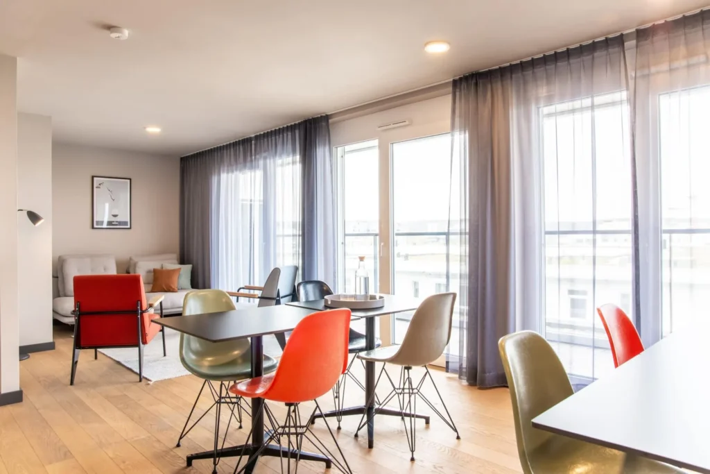 Lounge with seating group, dining table and large windows with curtains, ipartment Böblingen-Sindelfingen