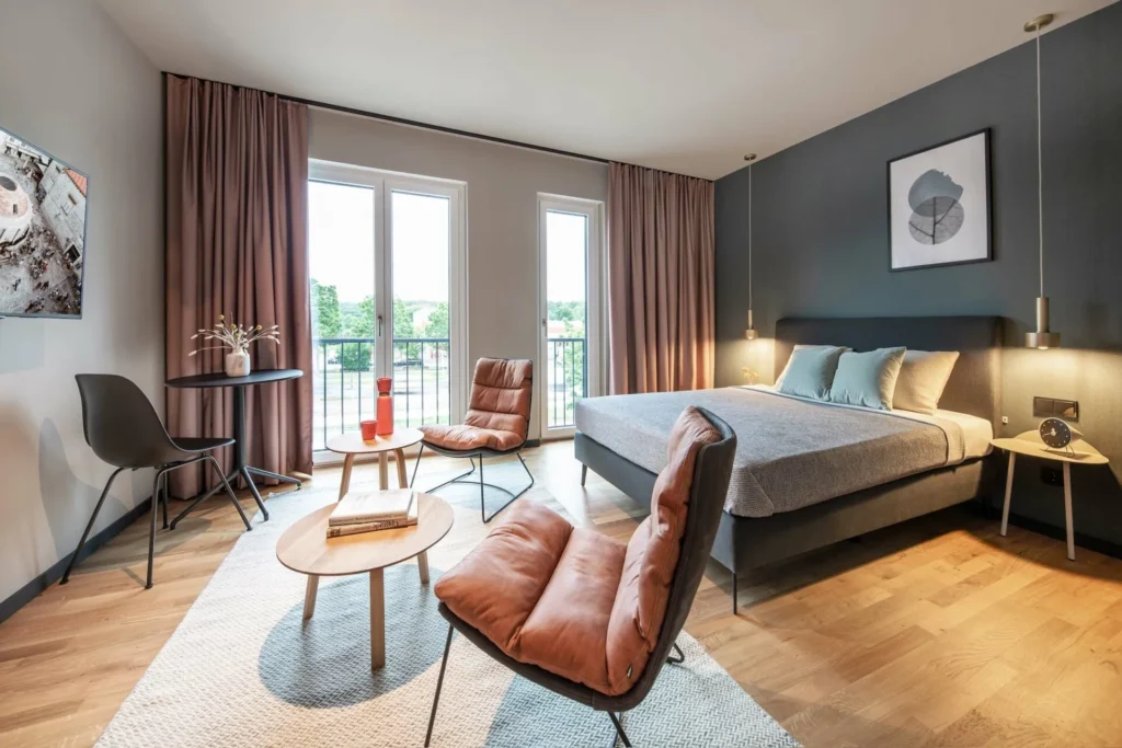 Living and sleeping area with leather sofas, double bed and balcony windows in Apartment S, apartment Braunschweig