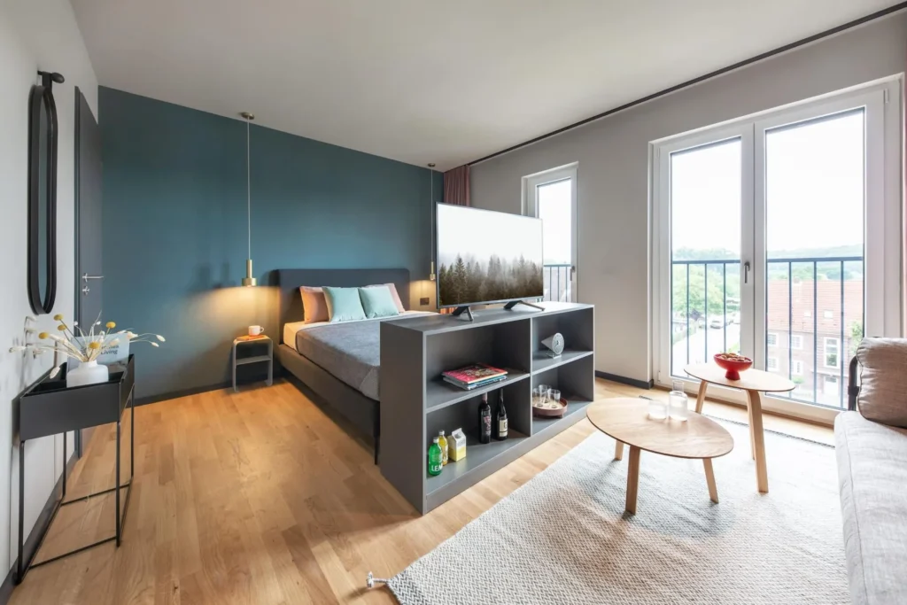 Double bed with a shelf as a divider, seating area and balcony door in Apartment S, apartment Braunschweig