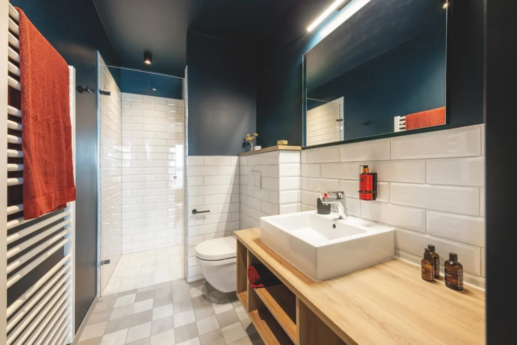 Bathroom with white subway tiles, wooden washbasin and shower cubicle in the XS apartment, ipartment Braunschweig