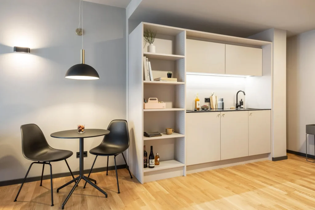 Dining area with two chairs in front of the bookcase and the kitchen area in the Medium apartment, ipartment Darmstadt