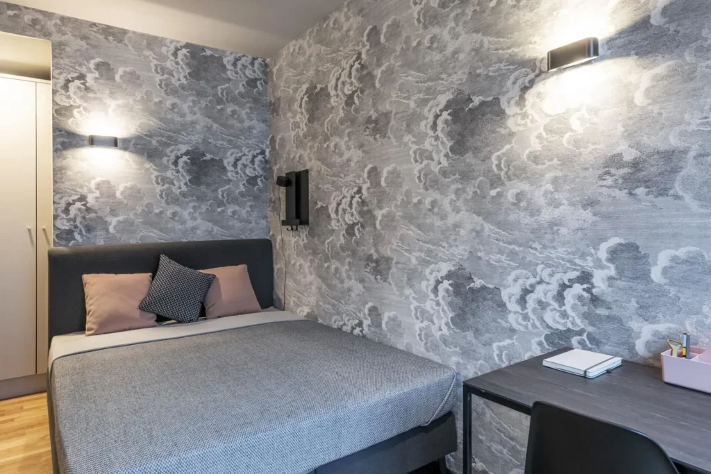 Sleeping area with double bed with a wall mural of clouds and a desk in the Medium apartment, ipartment Darmstadt