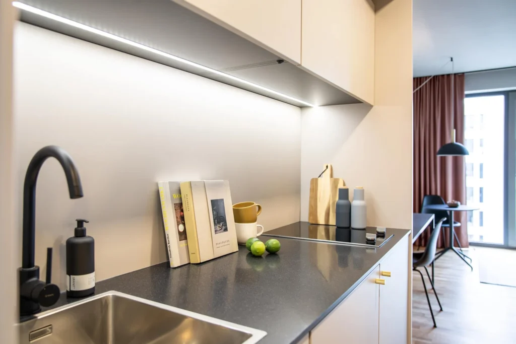 Kitchenette with black faucet, cooking surface and view to the dining area in the Smart apartment, ipartment Darmstadt