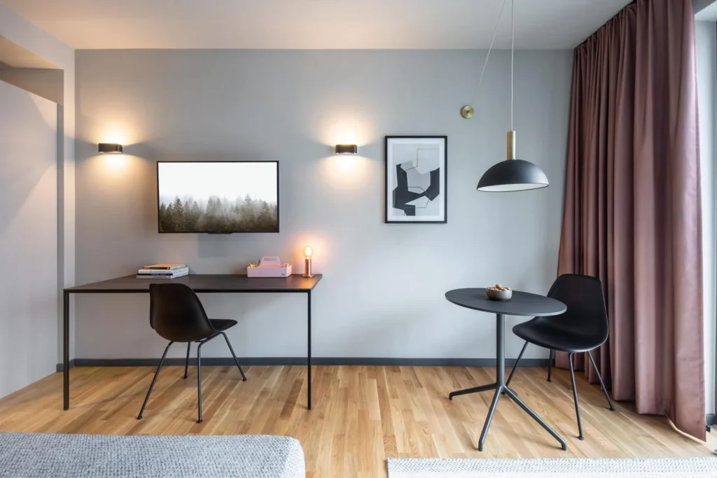 Desk with TV and dining table with two black chairs in the Smart apartment, ipartment Darmstadt