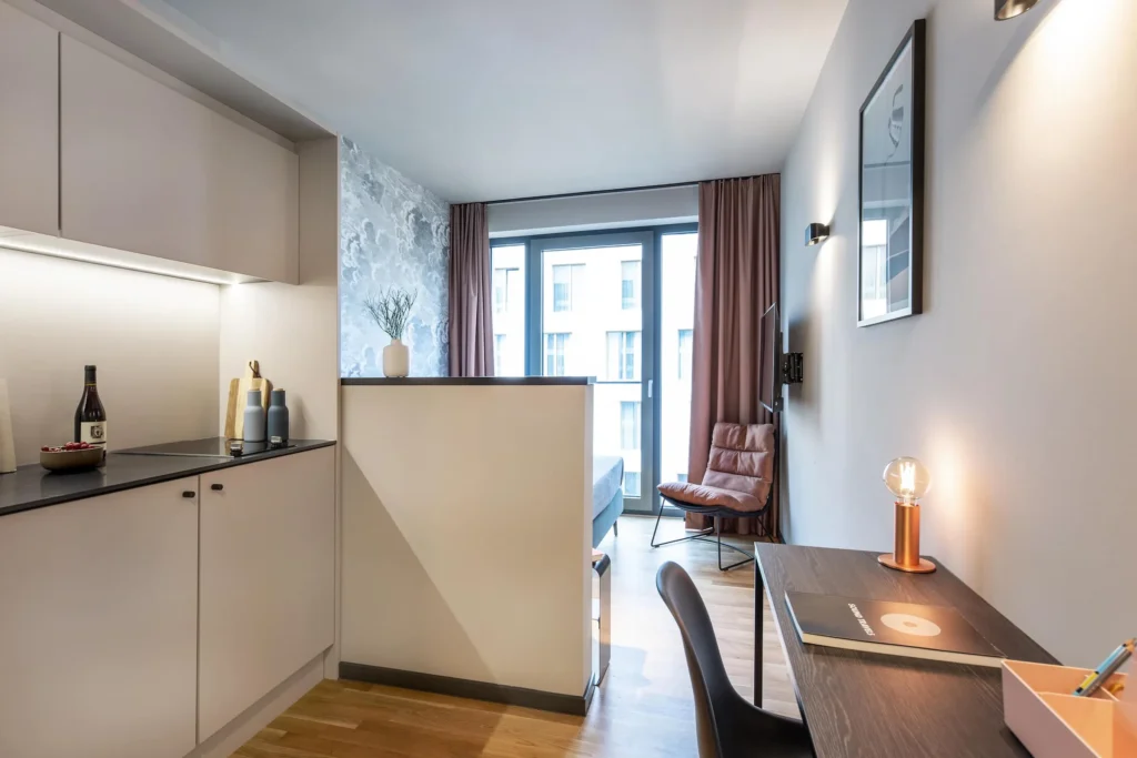 Studio with kitchenette, desk and bed in front of floor-to-ceiling window in the Xtra Smart apartment, ipartment Darmstadt