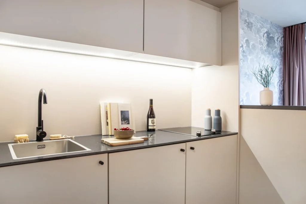 Kitchenette with sink, stove and under-cabinet light in the Xtra Smart apartment, ipartment Darmstadt