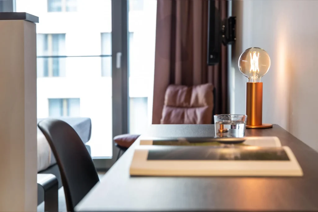 Desk with copper lamp and chair in front of the window in the Xtra Smart apartment, ipartment Darmstadt