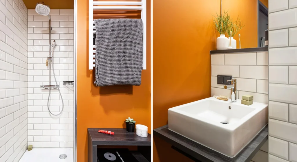 Bathroom with shower, towel heater and sink in front of an orange wall in the Xtra Smart apartment, ipartment Darmstadt