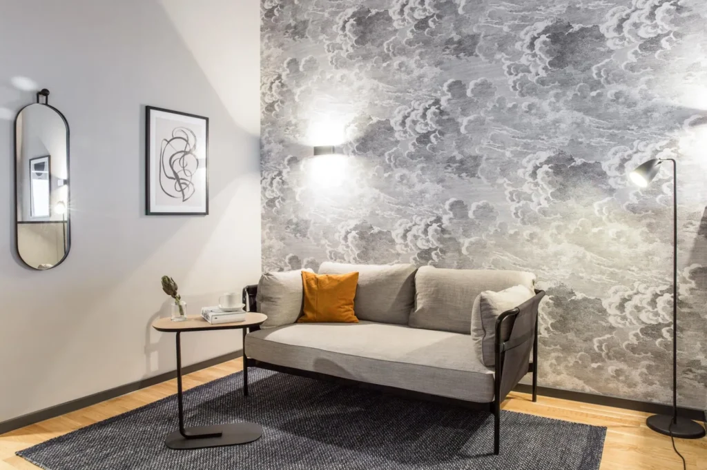 Sofa in front of the wall mural with a floor lamp and a wall mirror in the living area of the S apartment, apartment Frankfurt Airport