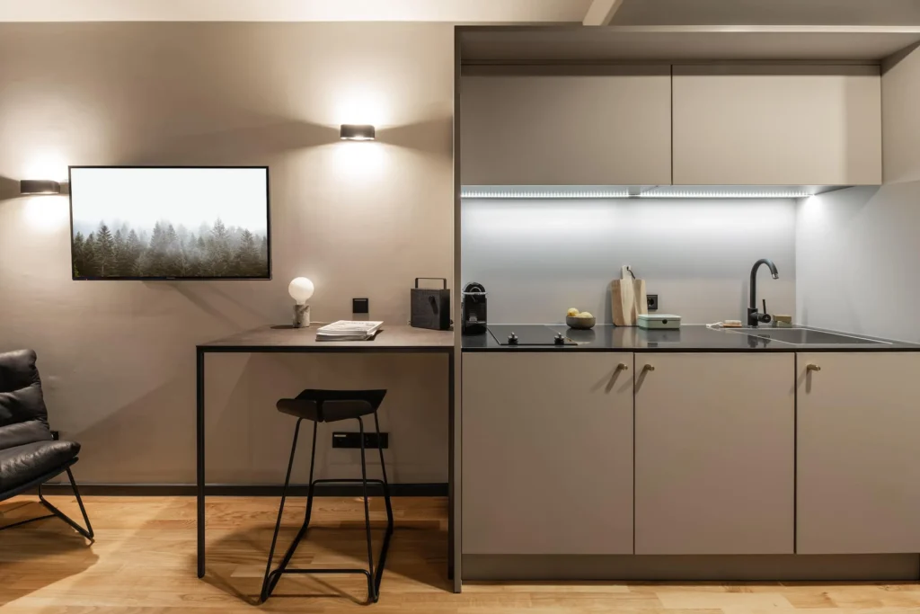 Kitchenette with cooking stove and desk with stool in the XS apartment, ipartment Frankfurt Airport
