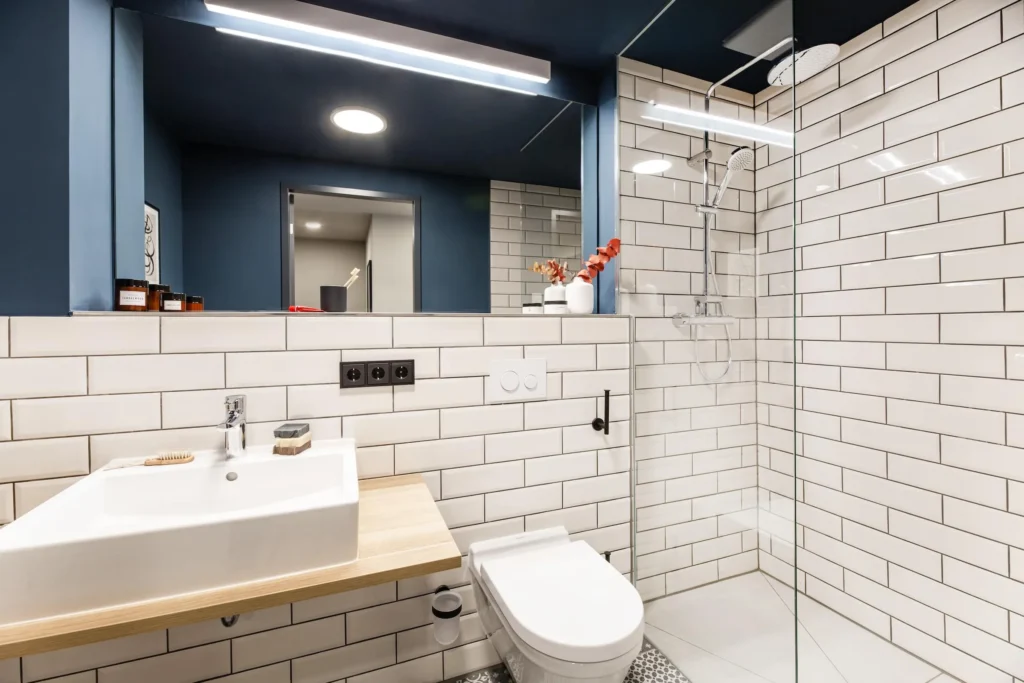 Bathroom with white subway tiles, washbasin with wooden top and shower in the XS apartment, ipartment Frankfurt Airport