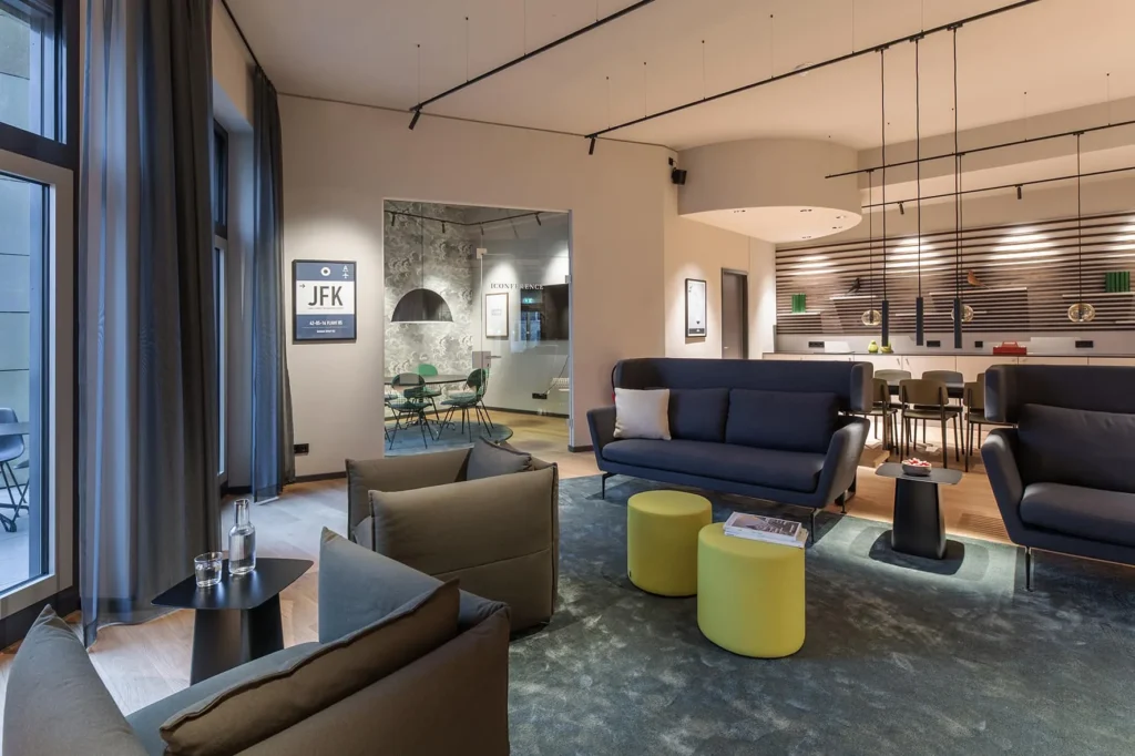 Vitra lounge with sofas, armchairs and lounge chairs in front of large windows, ipartment Frankfurt Airport