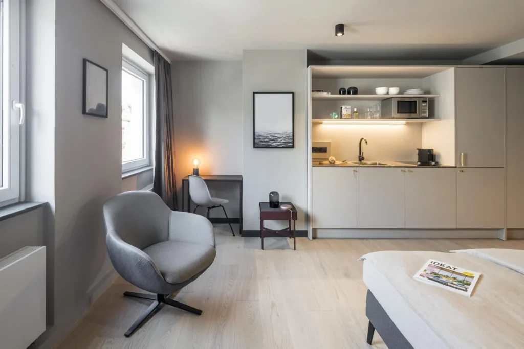Armchair, desk and kitchenette with bed end in the Medium apartment, ipartment Frankfurt Bahnhofsviertel