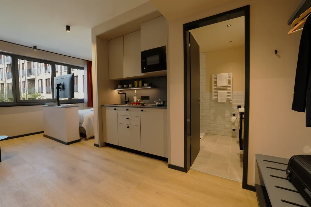 View through the apartment onto the kitchenette, wardrobe and the open bathroom, ipartment Frankfurt Eastside