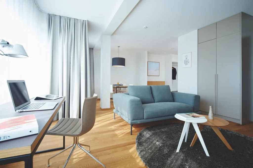 Living area with sofa, coffee table, desk and large built-in wardrobe in apartment L, ipartment Frankfurt Europaviertel