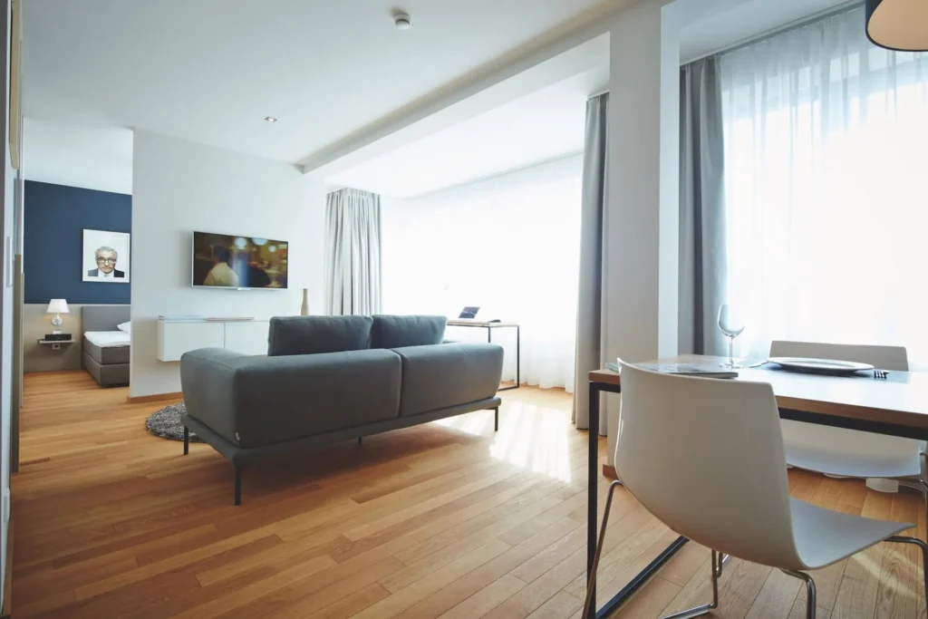 Sofa, dining table and TV with a view of the sleeping area in Apartment L, ipartment Frankfurt Europaviertel