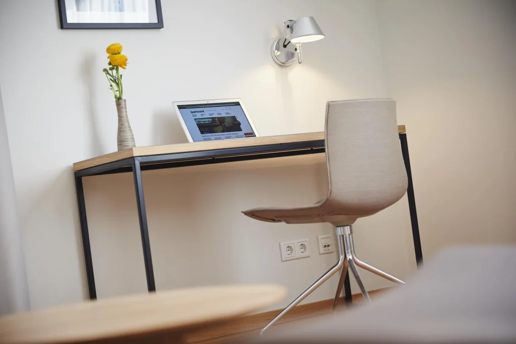 Desk with tablet, chair, table lamp and power outlets in front of a bright wall in the M apartment, ipartment Frankfurt Europaviertel