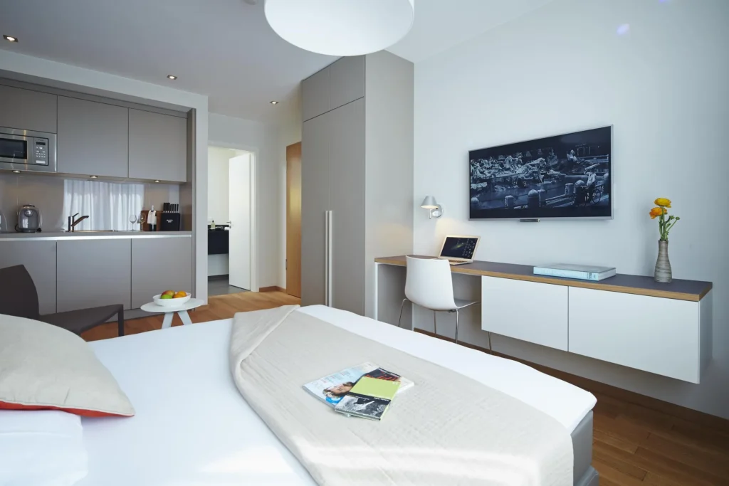 Bed, kitchenette, wall-mounted TV and desk in apartment S, ipartment Frankfurt Europaviertel