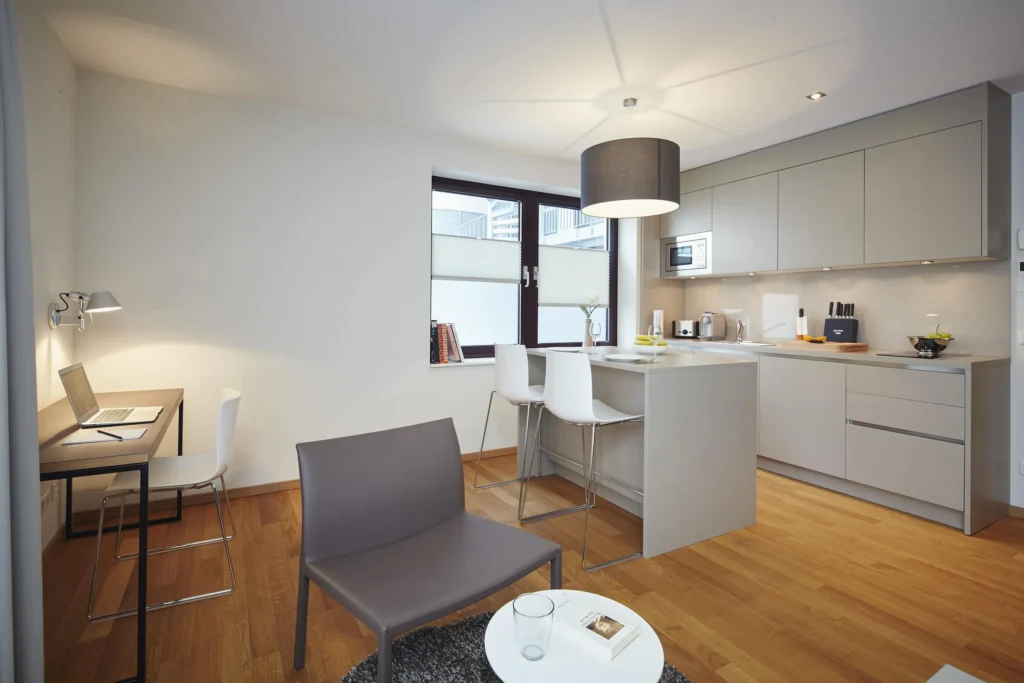 Bright kitchen with counter, work area by the window, and armchair in apartment S, Frankfurt Europaviertel
