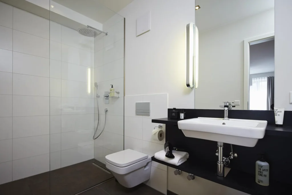 Bathroom with floor-level shower, sink and white wall tiles in Apartment S, ipartment Frankfurt Europaviertel