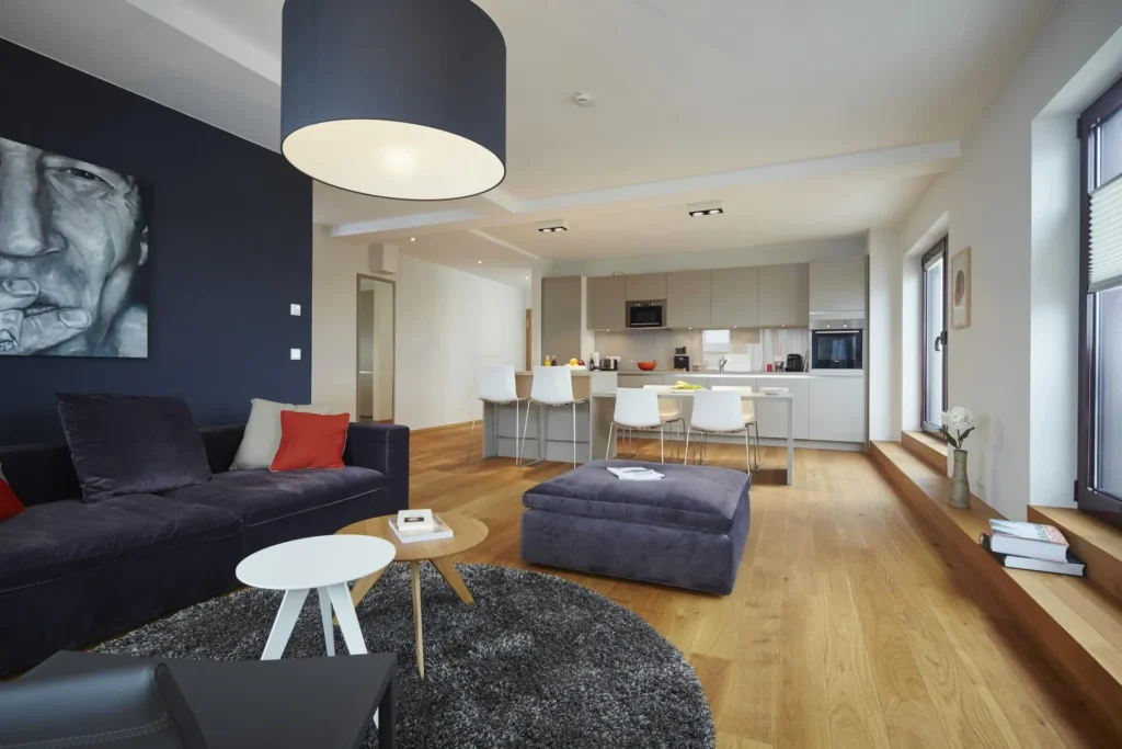 Open living area with sofa, stool and dining area next to the kitchen in the Penthouse Apartment XL, ipartment Frankfurt Europaviertel