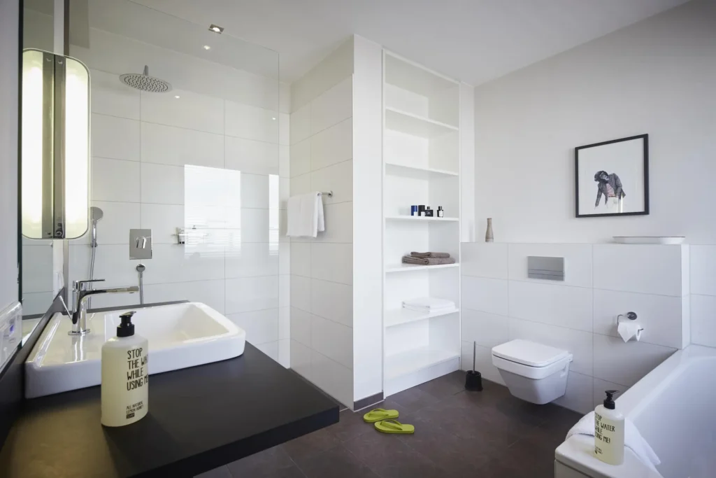 Bright bathroom with sink, bathtub, built-in shelves and rain shower in the XL apartment, ipartment Frankfurt Europaviertel