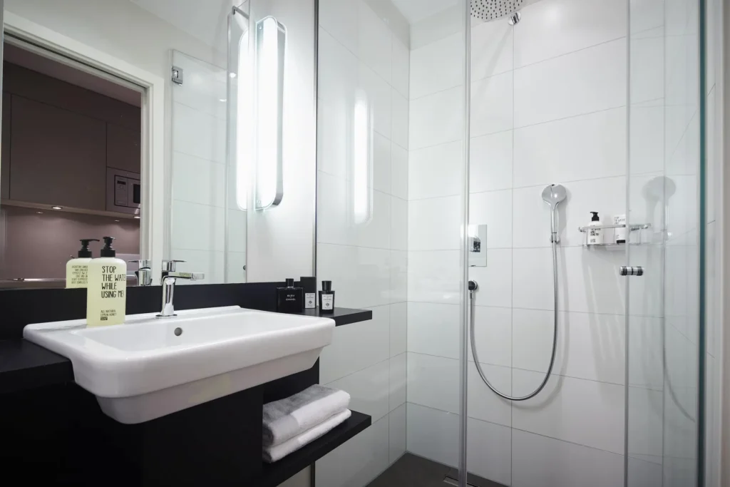 Bathroom with sink, glass shower and towels in the XS apartment, ipartment Frankfurt Europaviertel