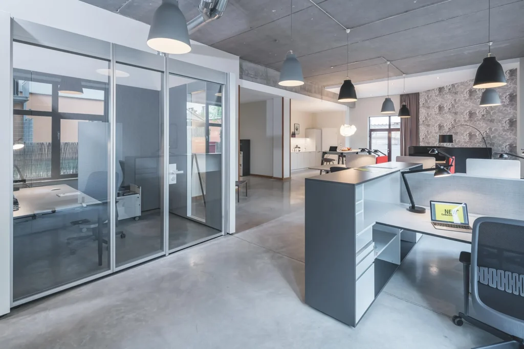 Glass office cubicles and reception desk in the coworking space with a concrete ceiling