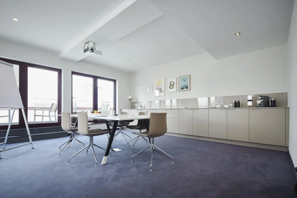 Bright conference room with projector, conference table and kitchenette with coffee machine, ipartment Frankfurt European Quarter