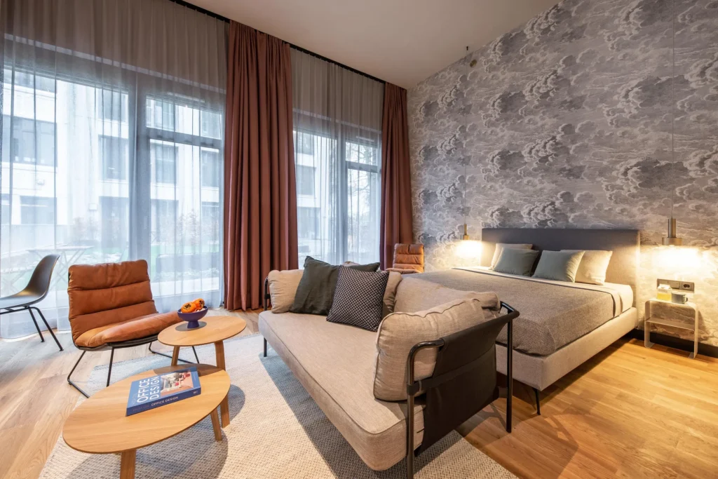 Living area with sofa, armchair and bed in the apartment Luxury, ipartment Hamburg Eimsbüttel, with a skylight and floor-to-ceiling windows