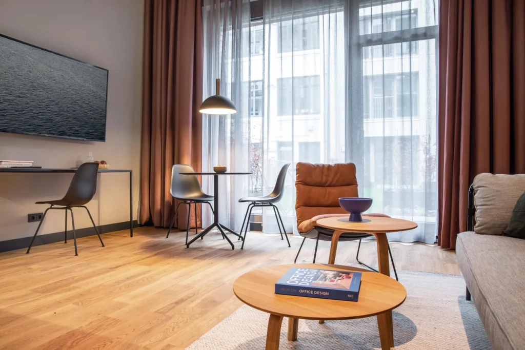 Sitting area with armchair and coffee table, TV and dining table in the apartment Luxury, ipartment Hamburg Eimsbüttel
